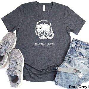 May include: Dark grey heather t-shirt with a white graphic of a pilot's helmet and the text "Don't Think, Just Do."