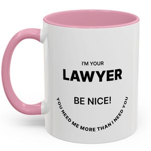 Puede incluir: Taza de cerámica blanca con interior y asa rosas. La taza presenta el texto "I'M YOUR LAWYER BE NICE! YOU NEED ME MORE THAN I NEED YOU" en negro y negrita. Un regalo humorístico.
