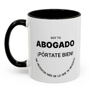 Puede incluir: Taza de cerámica blanca con interior y asa negros. La taza presenta el texto "SOY TU ABOGADO ¡PÓRTATE BIEN!" en negro, con texto adicional en semicírculo en la parte inferior. Un regalo perfecto para un abogado.