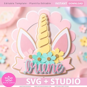 Op de afbeelding: Een gelaagde papieren eenhoorn taarttopper met een centrale gele hoorn, twee roze en witte oren, en turquoise en gele bloemen. Het ontwerp bevat een roze banner met de naam "briene" in turquoise cursief schrift op een roze geschulpte achtergrond.