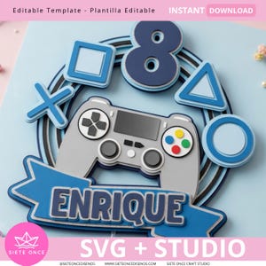 Puede incluir: Un adorno para pastel en capas con temática de videojuegos. Presenta un controlador gris, formas azules y el nombre "ENRIQUE" en una pancarta azul. También se incluye el número "8". El texto "SVG + STUDIO" está en la parte inferior.