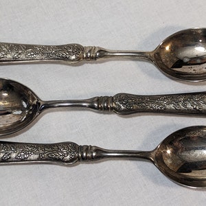 May include: Three silver spoons with ornate handles. The spoons have a floral design and are in good condition.
