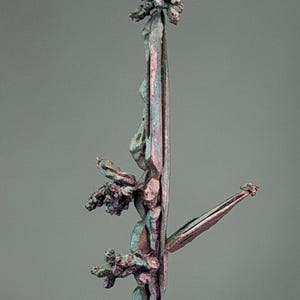 Può includere: Un esemplare di rame metallico grezzo caratterizzato da una struttura verticale allungata con un aspetto strutturato simile a un ramo. La superficie mostra un mix di toni rame rosso-bruno e patina verde ossidata, con grappoli cristallini sporgenti.