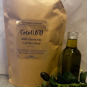 May include: A brown pouch with a label that reads "GOSHEN LOTION HANDCRAFTED SMALL BATCH SKIN CARE Coconot! 100% OLIVE OIL CASTILE SOAP 42 OUNCES"  To use: Dispense small amount onto hands, wash cloth or bath puff. Lather up and rinse well. Ingredients: Olea Europaea (Olive) Fruit Oil, Water Potassium Hydroxide. GOSHEN IN GOSHENLOTION.COM. A clear glass bottle of olive oil is next to the pouch.