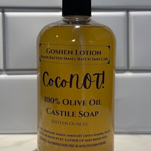 May include: A clear amber glass bottle with a black pump top dispenser. The bottle contains a yellow liquid and has a label that reads "Goshen Lotion Handcrafted Small Batch Skin Care Coconot! 100% Olive Oil Castile Soap Sixteen Ounces". The label also includes instructions for use and ingredients.