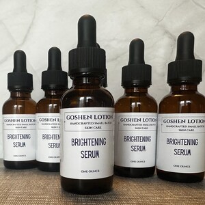 K&ouml;nnte beinhalten: F&uuml;nf bernsteinfarbene Glasflaschen mit Tropfern, jede gef&uuml;llt mit einer klaren Fl&uuml;ssigkeit. Die Flaschen sind mit "Goshen Lotion Handcrafted Small Batch Skin Care Brightening Serum One Ounce" beschriftet.