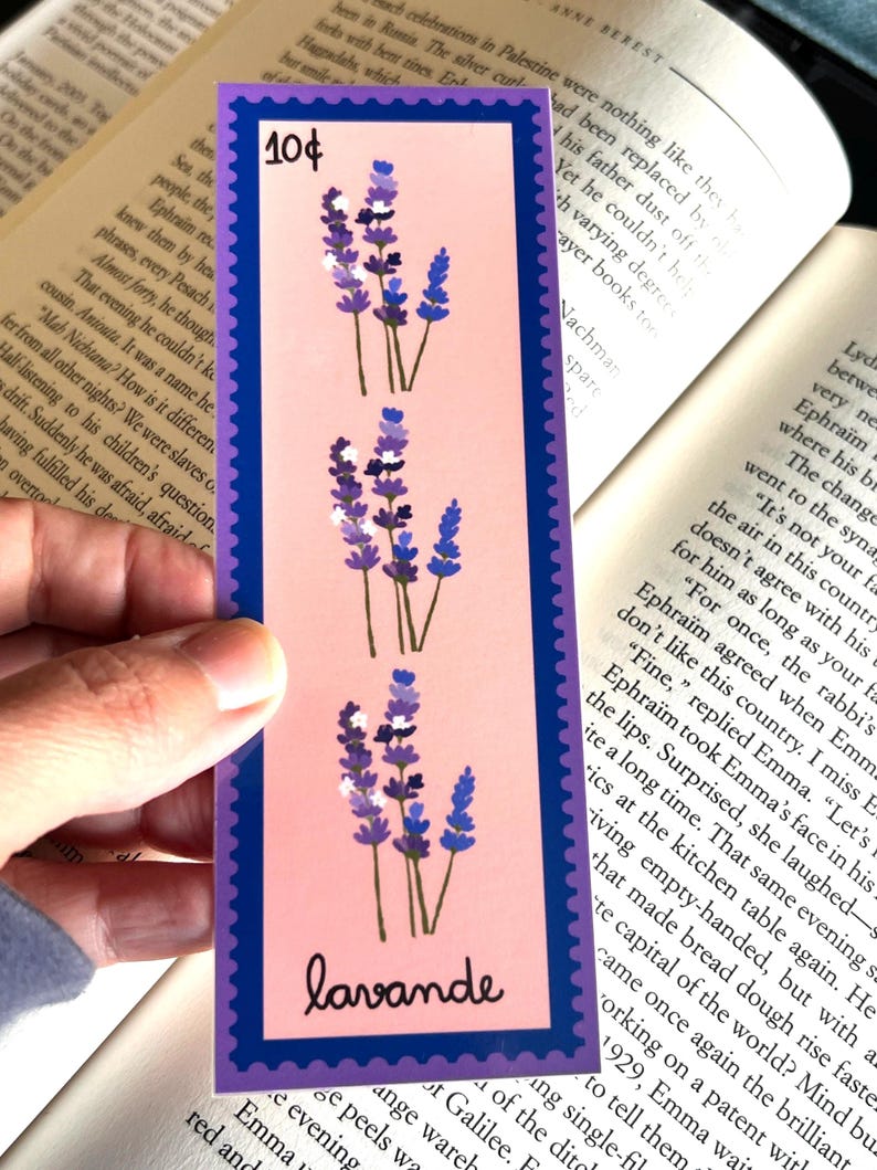 May include: A lavender bookmark with a pink background and a blue border. The bookmark features three sprigs of lavender with purple flowers and white accents. The text "10&cent;" is printed in the top left corner and "lavande" is printed in the bottom right corner.