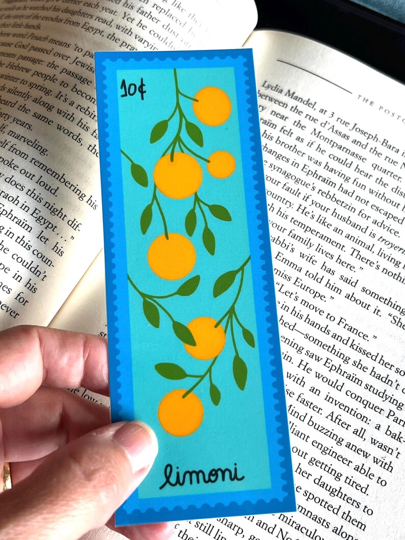 May include: A blue bookmark with a whimsical illustration of a branch of orange citrus fruit with green leaves. The bookmark has a white border and the word "limoni" in a white cursive font. The bookmark also has a blue stamp with the number "10&cent;" in white.