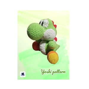 Può includere: Un personaggio Yoshi di uncinetto verde, bianco e arancione della serie di videogiochi Super Mario. Il Yoshi è seduto su uno sfondo verde con il testo "Yoshi pattern" sotto.