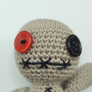 Puede incluir: Una mu&ntilde;eca vud&uacute; de crochet con un bot&oacute;n rojo para un ojo, un bot&oacute;n negro para el otro ojo y una boca cosida negra. La mu&ntilde;eca lleva un coraz&oacute;n rojo.