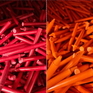 May include: A close-up image of two piles of red and orange crayons. The crayons are arranged in a random pattern, with some crayons sticking out from the pile.