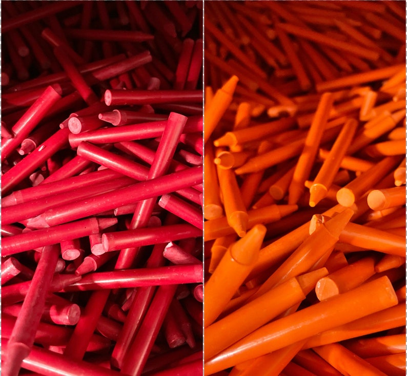 May include: A close-up image of two piles of red and orange crayons. The crayons are arranged in a random pattern, with some crayons sticking out from the pile.