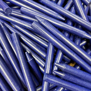May include: A pile of deep blue crayons, all lying together in a jumbled heap. The crayons are all the same size and shape, and they have a smooth, glossy finish.