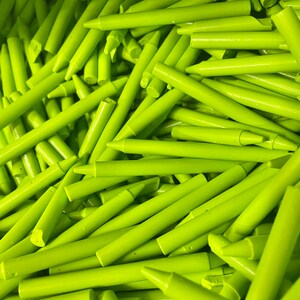 May include: A large pile of bright green crayons. The crayons are all the same size and shape, and they are arranged in a random pattern.