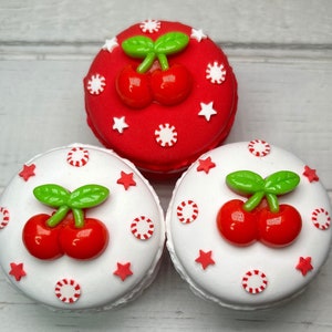 May include: Three round white and red cake pops decorated with white stars, red and white candy canes, and green and red cherries.