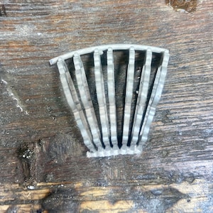 May include: A silver metal object with a curved shape and multiple vertical bars. The object is made of metal and has a smooth, shiny surface.