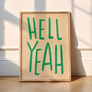 May include: A framed print with the words "HELL YEAH" written in green on a beige background.