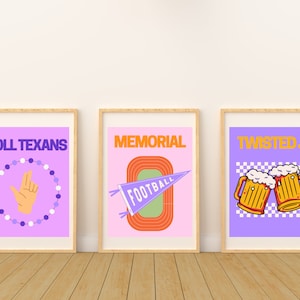 May include: Three framed prints with a purple background. The first print says "Roll Texans" and features a hand making the "hook 'em horns" gesture. The second print says "Memorial" and features a stylized football field with a pennant. The third print says "Twisted J" and features two cartoon beer mugs.