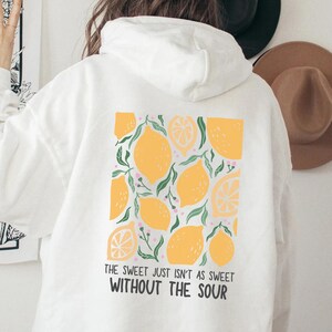 K&ouml;nnte beinhalten: Wei&szlig;er Hoodie mit einem Zitronendruck und dem Text "The sweet just isn't as sweet without the sour".