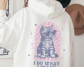 May include: White hooded sweatshirt with a graphic of a cat wearing sunglasses and the text "I do what I want".