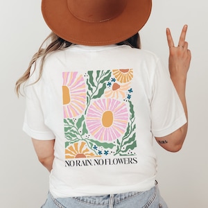 May include: White t-shirt with a floral graphic and the text "NO RAIN, NO FLOWERS".