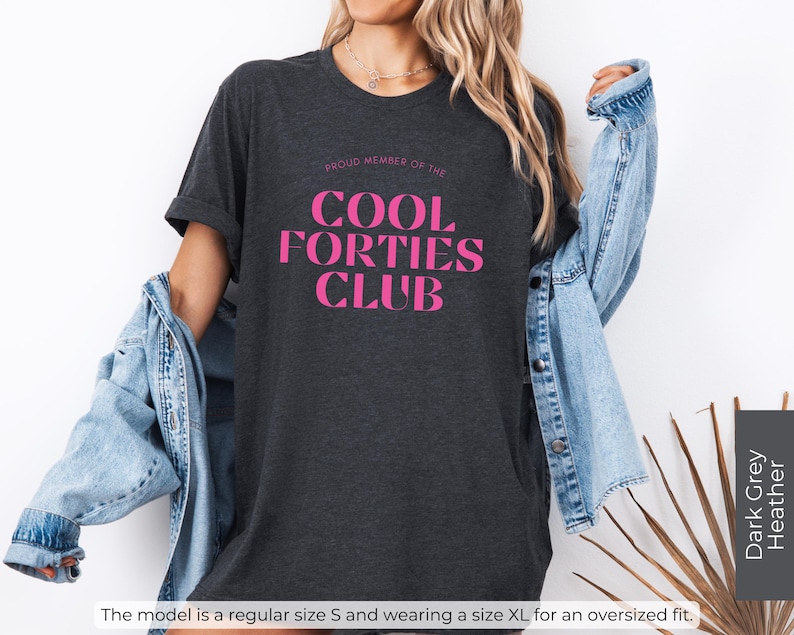 May include: Dark grey heather t-shirt with the text "Proud Member of the Cool Forties Club" in pink lettering.
