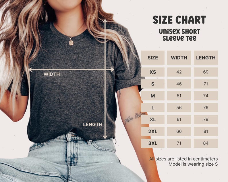 K&ouml;nnte beinhalten: Gr&ouml;&szlig;entabelle f&uuml;r ein Unisex-T-Shirt mit kurzen &Auml;rmeln. Die Tabelle zeigt die Breite und L&auml;nge in Zentimetern f&uuml;r die Gr&ouml;&szlig;en XS bis 3XL. Das Model tr&auml;gt Gr&ouml;&szlig;e S.