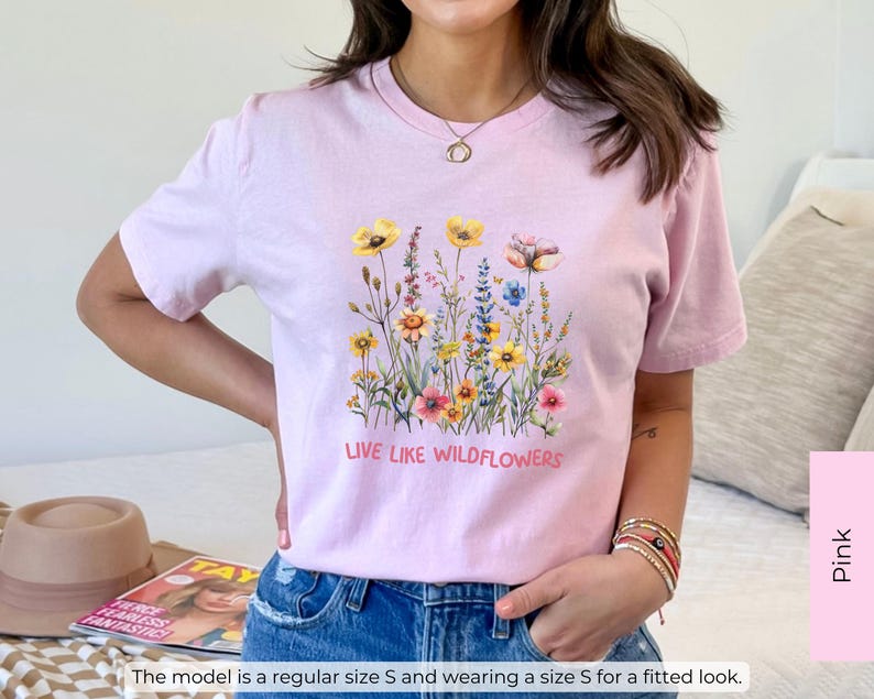 Puede incluir: Camiseta rosa con un dise&ntilde;o floral y el texto "Live Like Wildflowers".