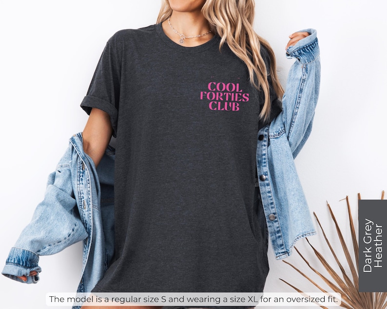 May include: A dark grey heather t-shirt with the text "COOL FORTIES CLUB" in pink lettering.