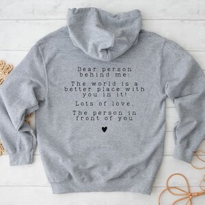 May include: Gray hooded sweatshirt with a message printed on the back: "Dear person behind me: The world is a better place with you in it! Lots of love, The person in front of you".