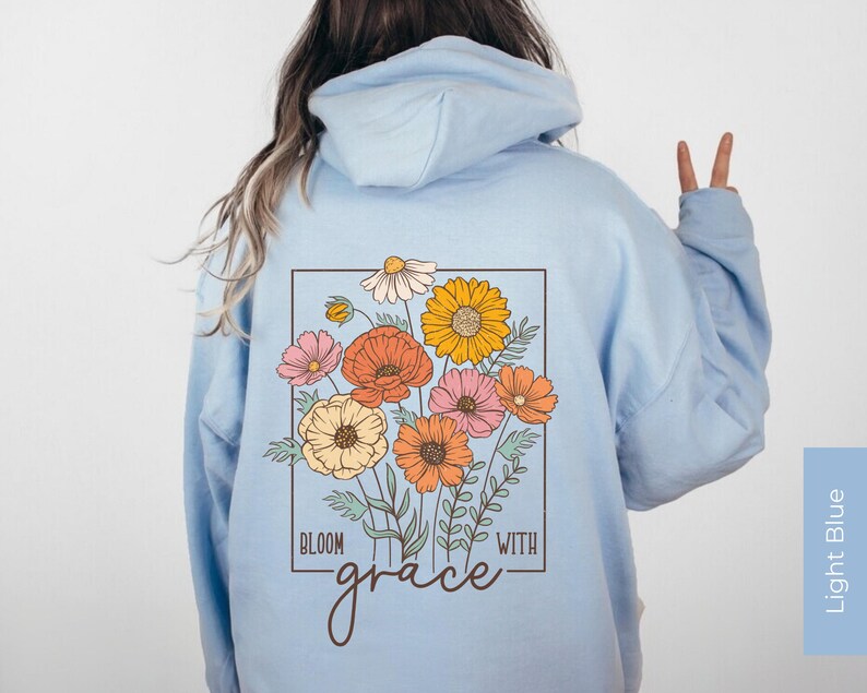 May include: Light blue hoodie with a floral design and the text "Bloom with grace" on the back.