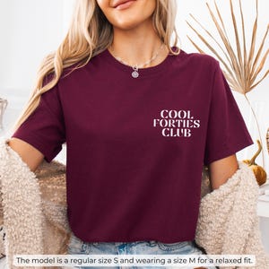 May include: A maroon t-shirt with white text that reads "Cool Forties Club".