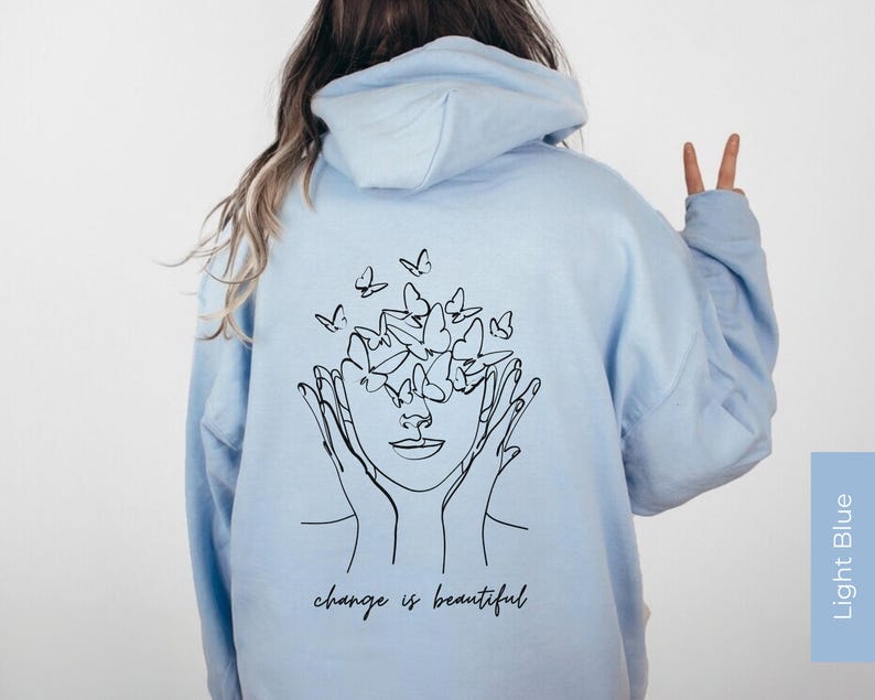 May include: Light blue hoodie with a black line drawing of a face with butterflies around it. The text "change is beautiful" is printed below the drawing.