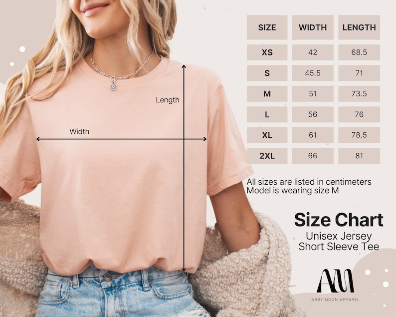 May include: A light peach-colored Unisex Jersey Short Sleeve Tee is shown with a size chart. The chart lists sizes XS to 2XL, with measurements in centimeters. The model is wearing size M. The brand name is Abby Moon Apparel.