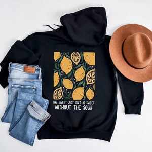 K&ouml;nnte beinhalten: Schwarzer Hoodie mit einem Zitronendruck und dem Text "The sweet just isn't as sweet without the sour".