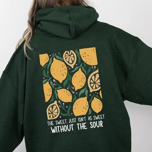 K&ouml;nnte beinhalten: Gr&uuml;n-schwarzer Kapuzenpullover mit einem Zitronen-Motiv und dem Text "The sweet just isn't as sweet without the sour".