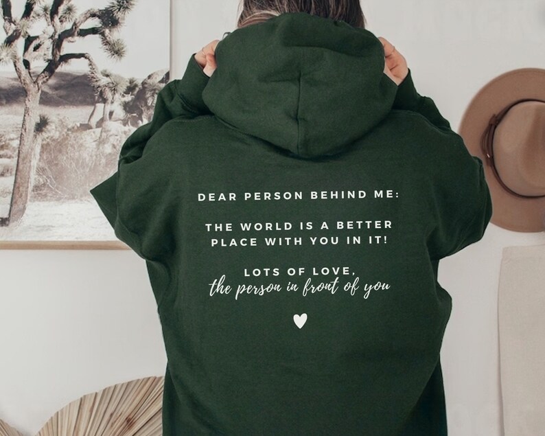 Pu&ograve; includere: Felpa con cappuccio verde scuro con testo bianco che dice "Cara persona dietro di me: Il mondo &egrave; un posto migliore con te dentro! Tanto amore, la persona davanti a te".