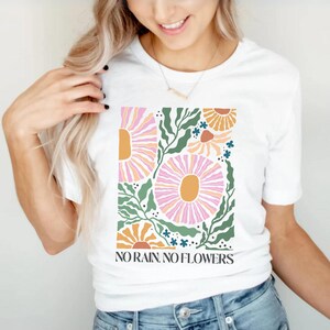 May include: White t-shirt with a floral design and the text "NO RAIN, NO FLOWERS".