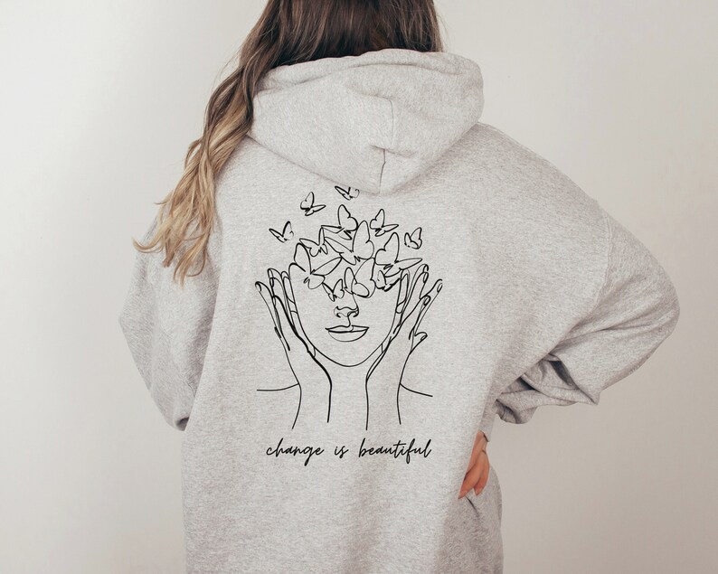 May include: Gray hooded sweatshirt with a black line drawing of a face with butterflies around it. The text "change is beautiful" is printed below the drawing.
