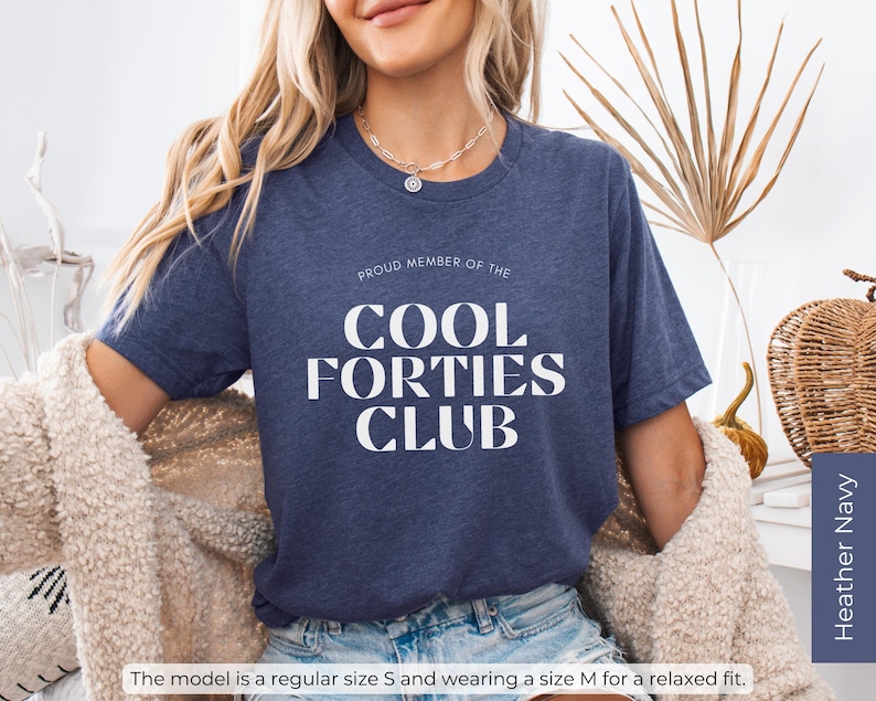May include: A navy blue t-shirt with the text "Proud Member of the Cool Forties Club" in white lettering.