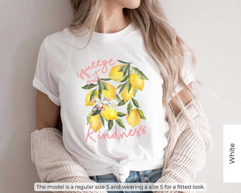 K&ouml;nnte beinhalten: Wei&szlig;es T-Shirt mit einem Motiv aus Zitronen und Bl&auml;ttern. Der Text "Squeeze out Kindness" ist in Pink auf dem Shirt gedruckt.