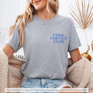 May include: Gray t-shirt with the text "Cool Forties Club" in blue lettering.