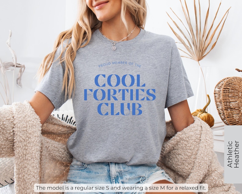 May include: Gray t-shirt with the text "PROUD MEMBER OF THE COOL FORTIES CLUB" in blue letters.