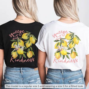 K&ouml;nnte beinhalten: Zwei T-Shirts mit einem Zitronenmotiv und dem Text "squeeze out kindness". Ein Shirt ist schwarz und das andere ist wei&szlig;.