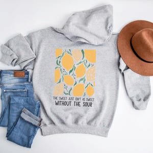 K&ouml;nnte beinhalten: Ein grauer Kapuzenpullover mit einem Zitronendruck und dem Text "The sweet just isn't as sweet without the sour".