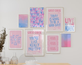 May include: A collection of eight framed prints with pink and blue color schemes. The prints feature various motivational quotes and designs, including hearts, a guest check, and a ticket stub. The prints are arranged on a white wall above a wooden table.