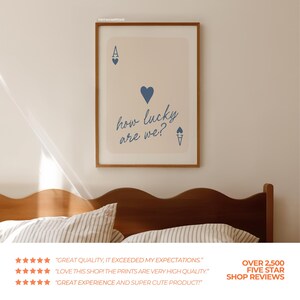 Pu&ograve; includere: Una stampa d'arte stampabile beige con un design di carta da gioco di asso di cuori blu. Il testo sulla stampa recita "how lucky are we?"