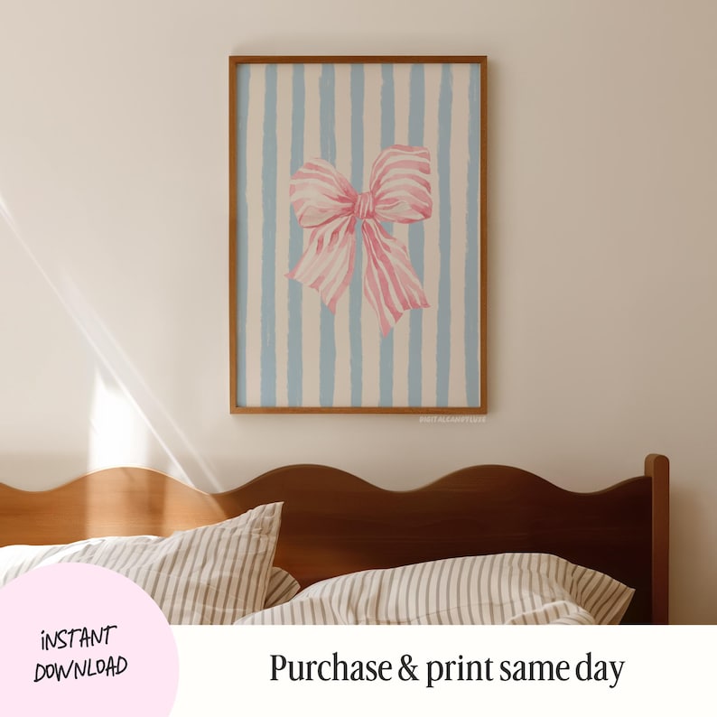 May include: A printable digital download of a pink bow on a blue and white striped background. The image is framed and hanging on a wall above a wooden bed with striped bedding.