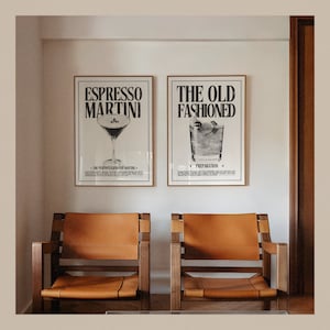 May include: Two framed black and white prints of cocktail recipes. The prints are hung on a white wall above two brown leather chairs. The left print features the text "Espresso Martini" and a drawing of a cocktail. The right print features the text "The Old Fashioned" and a drawing of a cocktail.