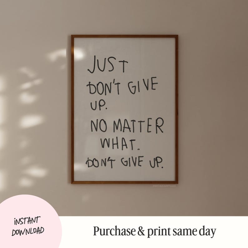 May include: A framed print with the text "JUST DON'T GIVE UP. NO MATTER WHAT. DON'T GIVE UP." in black handwritten font on a white background.